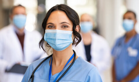 Happy nurse with face mask smiling at hospital