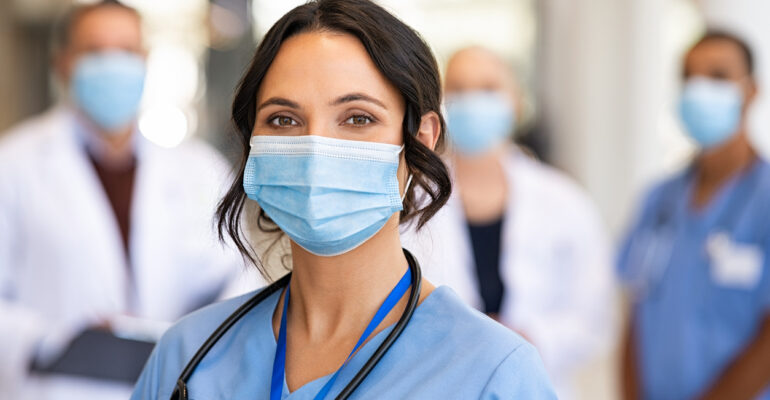 Happy nurse with face mask smiling at hospital